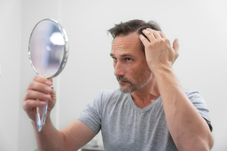 A man examining his hair in the mirror after starting hair loss treatments at PracticeRx."